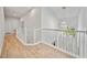 Bright hallway with white railings, hardwood floors, and a view of the neighborhood at 18004 Avalon Ln, Tampa, FL 33647