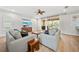 Bright living room features wood floors, ceiling fan, and sliding glass doors to the screened patio at 18004 Avalon Ln, Tampa, FL 33647