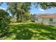 Large backyard with lush lawn, mature trees, and a partial view of the screened in pool area at 18561 Winding Oaks Blvd, Hudson, FL 34667