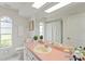 Bright bathroom featuring retro pink counters, arched windows, and a bathtub with shower at 18561 Winding Oaks Blvd, Hudson, FL 34667