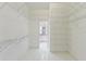 Spacious walk-in closet featuring white shelving units and tile flooring, leading to the bathroom at 18561 Winding Oaks Blvd, Hudson, FL 34667