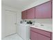 Functional laundry area featuring mauve-colored cabinets, washer, dryer, and utility sink at 18561 Winding Oaks Blvd, Hudson, FL 34667