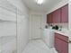 Clean laundry room with washer, dryer, utility sink, shelving, and pink cabinets for storage at 18561 Winding Oaks Blvd, Hudson, FL 34667