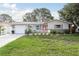 Inviting home with a manicured lawn, red door, white picket fence, and an attached garage at 2005 Jefferson Ave, Dunedin, FL 34698