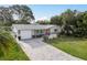 Charming single-story home featuring a well-maintained front yard, brick driveway, and an inviting red front door at 2005 Jefferson Ave, Dunedin, FL 34698
