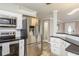 Kitchen area featuring modern stainless steel appliances, white cabinets, and a breakfast bar overlooking the living space at 2005 Jefferson Ave, Dunedin, FL 34698