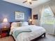 Cozy bedroom featuring a blue accent wall, plush bedding, and natural light, creating a tranquil retreat at 28410 Wildlife Ln, Brooksville, FL 34602