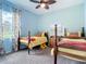 A shared bedroom with light blue walls, ceiling fan, and two twin beds at 28410 Wildlife Ln, Brooksville, FL 34602
