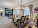 Elegant dining room featuring a chandelier, a table set for six, and large windows with decorative curtains at 28410 Wildlife Ln, Brooksville, FL 34602