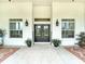 Inviting front porch with double doors, sconces, windows, potted plants, and stylish seating at 28410 Wildlife Ln, Brooksville, FL 34602