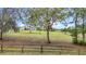Expansive front yard featuring lush green grass, mature trees, and a charming fence surrounding the property at 28410 Wildlife Ln, Brooksville, FL 34602