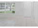 Bright living room featuring neutral tile flooring, a front-facing window, and a white front door at 456 Summer Sails Dr, Valrico, FL 33594