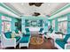 Bright aqua lounge area with white wicker chairs, ceiling fans and compass rose on the wood floor at 4984 Beach Se Dr # B, St Petersburg, FL 33705