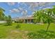 Well-maintained backyard featuring a lush lawn, mature trees, tropical foliage, and an enclosed patio at 608 Fort Duquesna Dr, Sun City Center, FL 33573