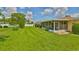 Expansive backyard with manicured lawn, white fence, mature trees, and enclosed patio for outdoor enjoyment at 608 Fort Duquesna Dr, Sun City Center, FL 33573