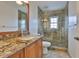 Bathroom with granite countertop, wood cabinets, toilet, and glass enclosed shower with patterned tile at 608 Fort Duquesna Dr, Sun City Center, FL 33573