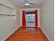 Bedroom with laminate flooring, one window with red drapes, an open shelf and a view to an outdoor patio at 608 Fort Duquesna Dr, Sun City Center, FL 33573