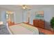 Bright main bedroom featuring wood floors, dresser, ceiling fan, and en-suite bathroom access at 608 Fort Duquesna Dr, Sun City Center, FL 33573