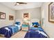 Bright bedroom with two beds, ceiling fan, and decorative paintings at 6327 Positano Ct, Sarasota, FL 34243
