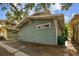 Rear exterior view showcases the light blue wood siding and gravel area, complemented by lush greenery at 711 S Bungalow Ter, Tampa, FL 33606