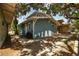 Side view of charming blue home featuring shingle siding, white trim, and mature trees at 711 S Bungalow Ter, Tampa, FL 33606