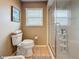 Bathroom showcasing a glass shower, toilet, and window with blinds at 760 Capri Blvd, Treasure Island, FL 33706