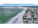 Wide aerial perspective of a sandy beach, highlighting the calm ocean and waterfront buildings including condos and resorts at 760 Capri Blvd, Treasure Island, FL 33706
