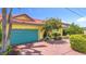 Quaint home with vibrant landscaping, red brick driveway, and striking blue garage door at 760 Capri Blvd, Treasure Island, FL 33706