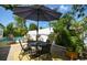 Outdoor patio features a table, umbrella, and seating next to a pool, perfect for relaxation at 7699 92Nd St, Seminole, FL 33777