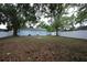 Spacious backyard featuring a blue house, a white fence, and mature trees, offering ample outdoor space at 8405 N Willow Ave, Tampa, FL 33604