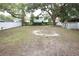Large, partially grassy backyard with white perimeter fence and mature trees, a blank canvas for recreation and relaxation at 8405 N Willow Ave, Tampa, FL 33604