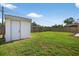 Backyard with large green grass area, storage shed, partial patio, and wooden fence at 8939 90Th Ave, Seminole, FL 33777