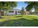 Eye-level exterior shot of a home with mature trees, a well-manicured lawn, and unique wooden architectural details at 8939 90Th Ave, Seminole, FL 33777