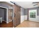 Main bedroom view showcasing wood-look tile, sliding barn door to bath, and sun-filled window at 932 Woodbridge Ct, Safety Harbor, FL 34695