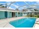 Backyard pool area with a screened-in pool next to a blue house at 105 E North Branch Rd, Ruskin, FL 33570