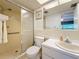 Bright bathroom featuring a shower, white vanity, and a large mirror reflecting the doorway at 1102 Cara Dr, Largo, FL 33771