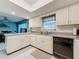 Kitchen with breakfast bar, white cabinetry, tile backsplash and modern appliances at 1102 Cara Dr, Largo, FL 33771