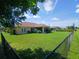 A large, grassy backyard is partially enclosed by a black chain-link fence and lush trees at 1185 Rio De Janeiro Ave, Punta Gorda, FL 33983