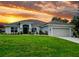 Charming single-story home boasts a well-manicured lawn and inviting curb appeal at sunset at 13045 Irwin Dr, Port Charlotte, FL 33953