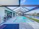 Inviting screened pool boasts clear blue water and a covered patio overlooking the serene waterfront view at 13045 Irwin Dr, Port Charlotte, FL 33953