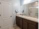 Well-lit bathroom featuring a wide mirror, modern vanity with storage, and tiled flooring at 14524 Dunrobin Dr, Wimauma, FL 33598