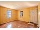Living room with yellow walls, two windows, damaged floors, and front door at 1520 S Michigan Ave, Clearwater, FL 33756