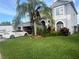 Two-story home with a well-manicured lawn, mature landscaping, and a palm tree in the front yard at 1521 Atami Ct, Wesley Chapel, FL 33544