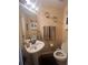 Cozy half bathroom featuring a pedestal sink, decorative mirror, and traditional fixtures at 1521 Atami Ct, Wesley Chapel, FL 33544
