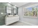 Bright bathroom featuring a double sink vanity, contemporary mirrors, and a large window providing natural light at 15722 Gardenside Ln, Tampa, FL 33624