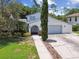 Charming home featuring a well-manicured lawn, mature trees, and an arched entryway leading to the front door at 15722 Gardenside Ln, Tampa, FL 33624
