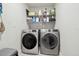 Functional laundry room with modern washer and dryer units and shelving at 15722 Gardenside Ln, Tampa, FL 33624