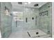 Modern walk-in shower with rainfall showerhead, mosaic tile flooring, and glass enclosure at 15722 Gardenside Ln, Tampa, FL 33624