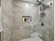 Modern shower with sleek gray tiling, built-in shelving for toiletries, and a glass enclosure for a spa-like experience at 15722 Gardenside Ln, Tampa, FL 33624