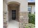 Covered front entry showcasing stone pillar accents and a black front door at 1827 Trillium Blvd, Brooksville, FL 34604